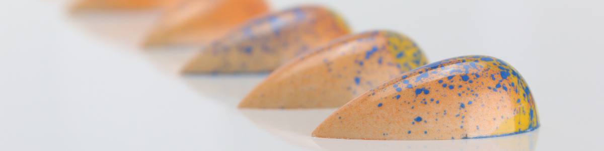 peach coloured chocolate bonbons with blue and yellow flecks on a white background